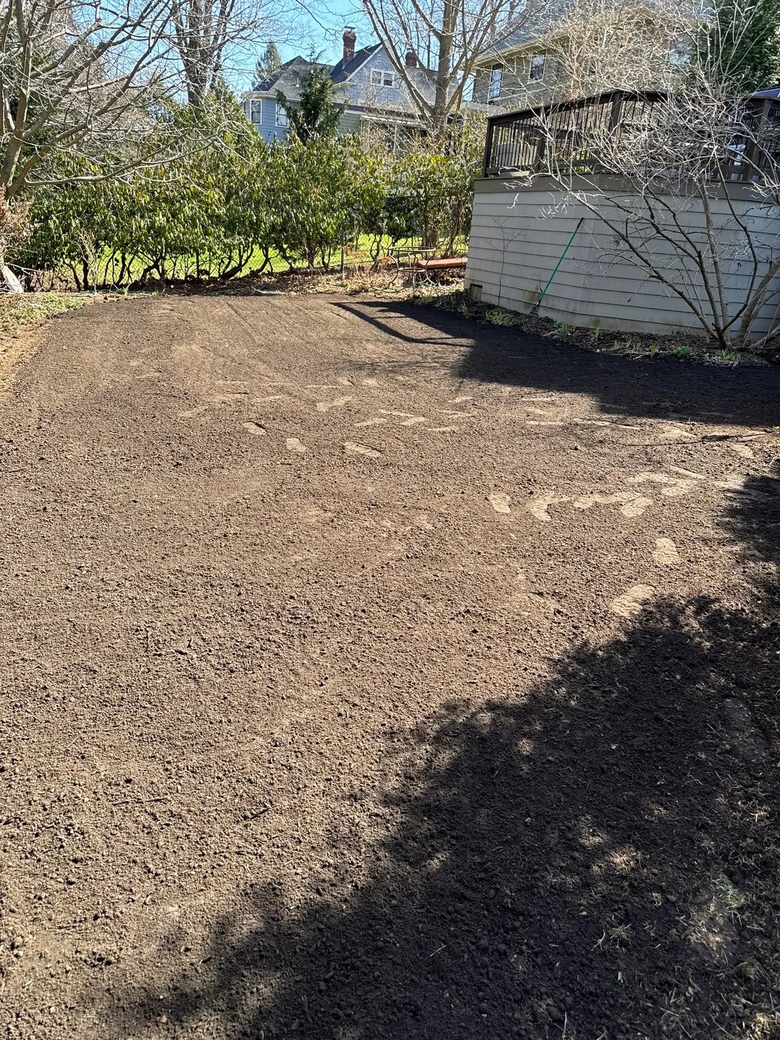 A yard graded to bare soil and leveled near a shed and utilities