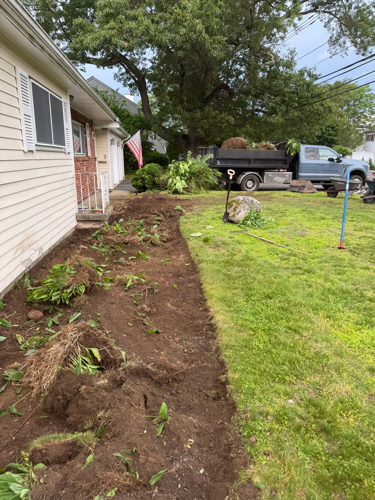 A tidy mulch bed running along a house foundation after a cleanup in Concord, MA