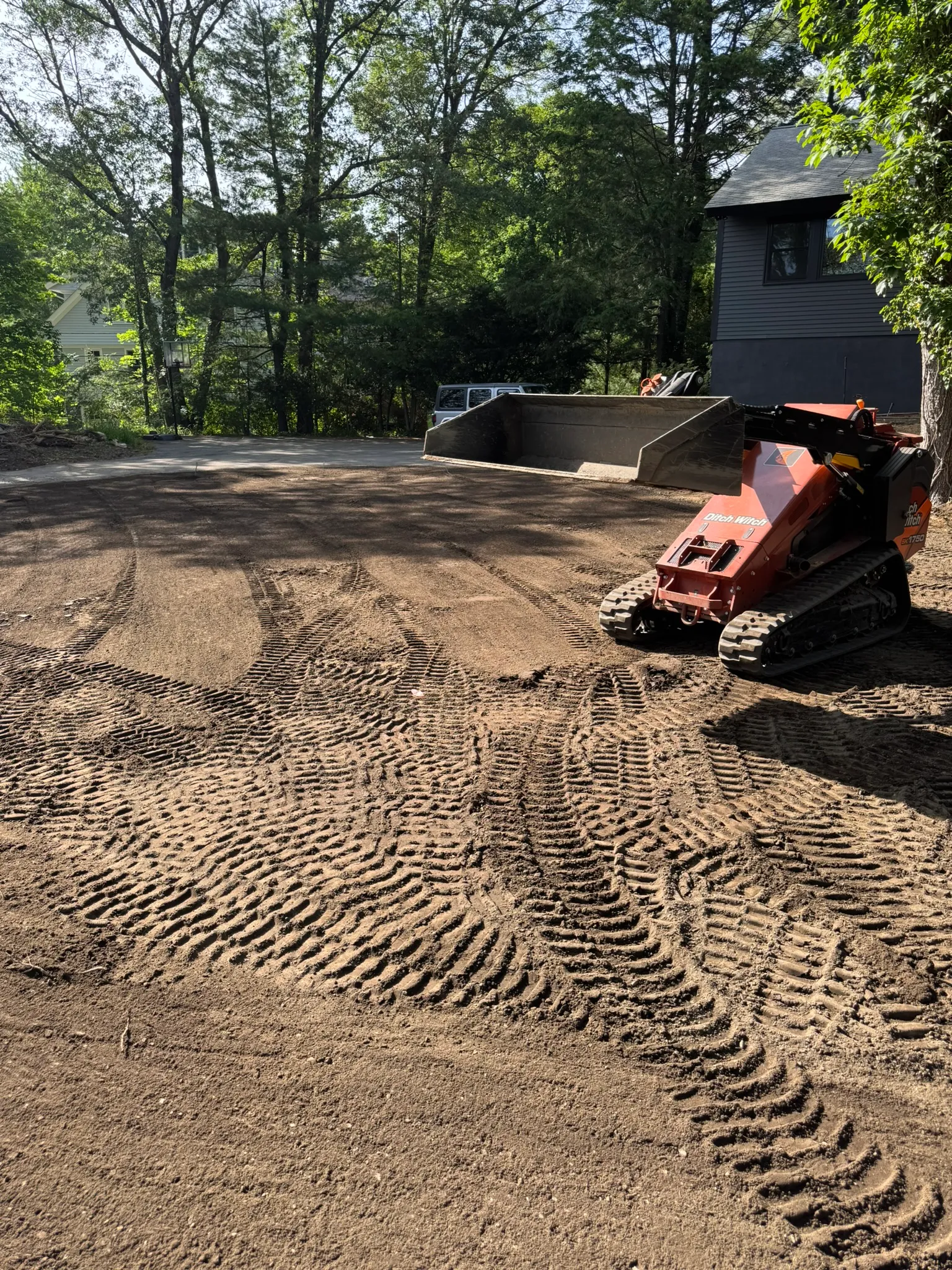 A freshly graded dirt yard with track marks after excavation work in Concord, MA