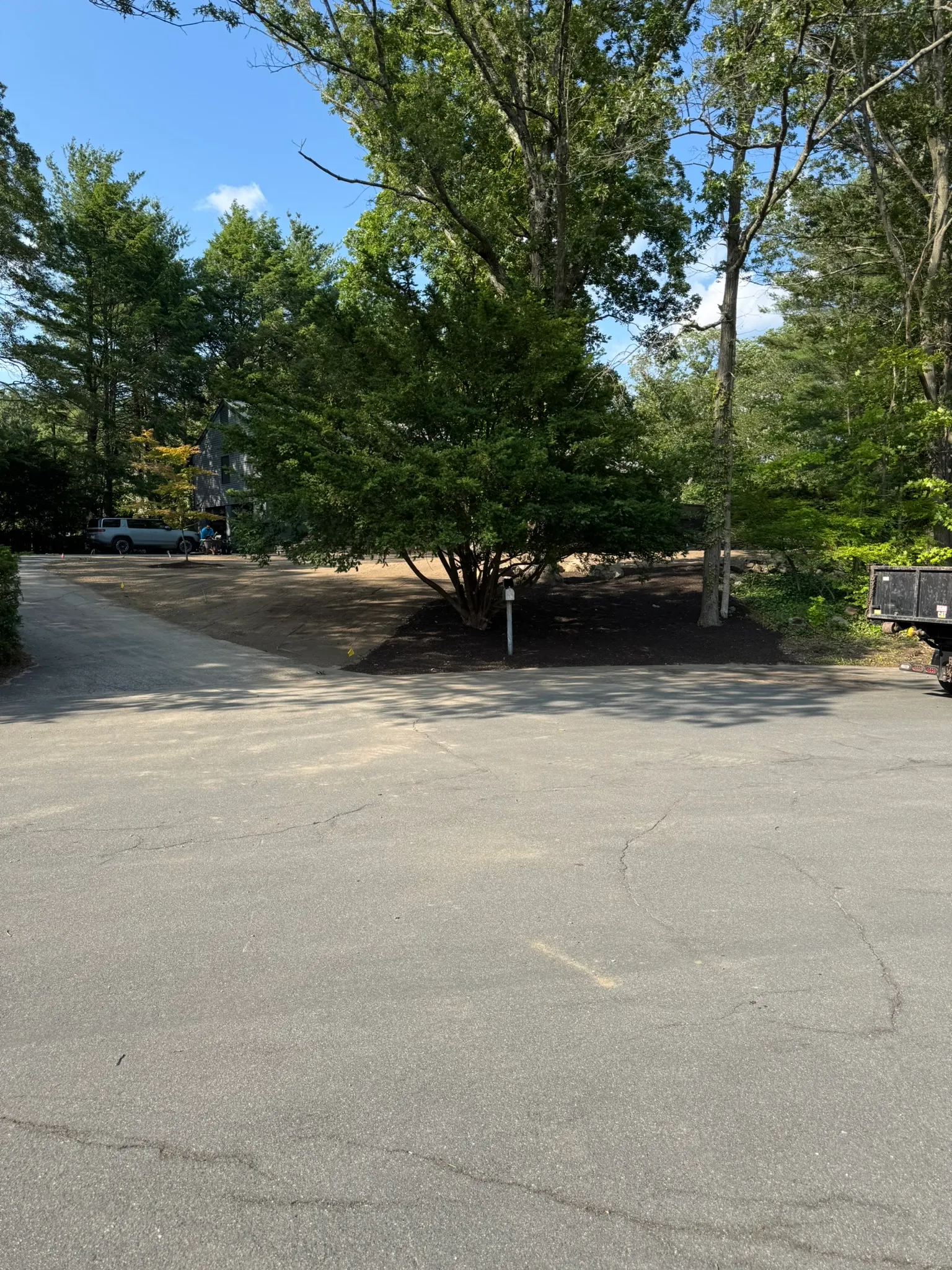 A cleared and mulched grounds area beside a commercial parking lot in Burlington, MA