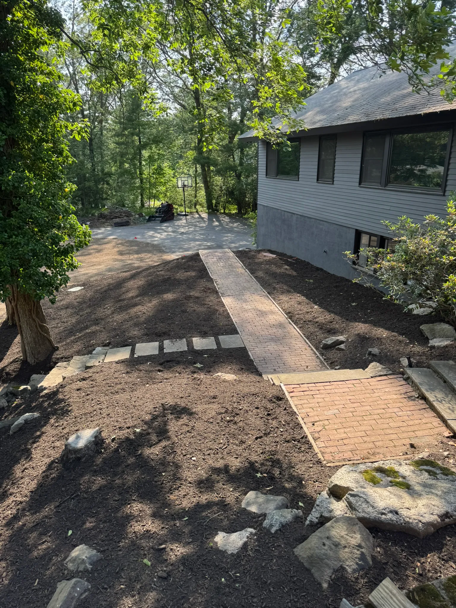 A new stone walkway and regraded yard partway through hardscape construction in Concord, MA