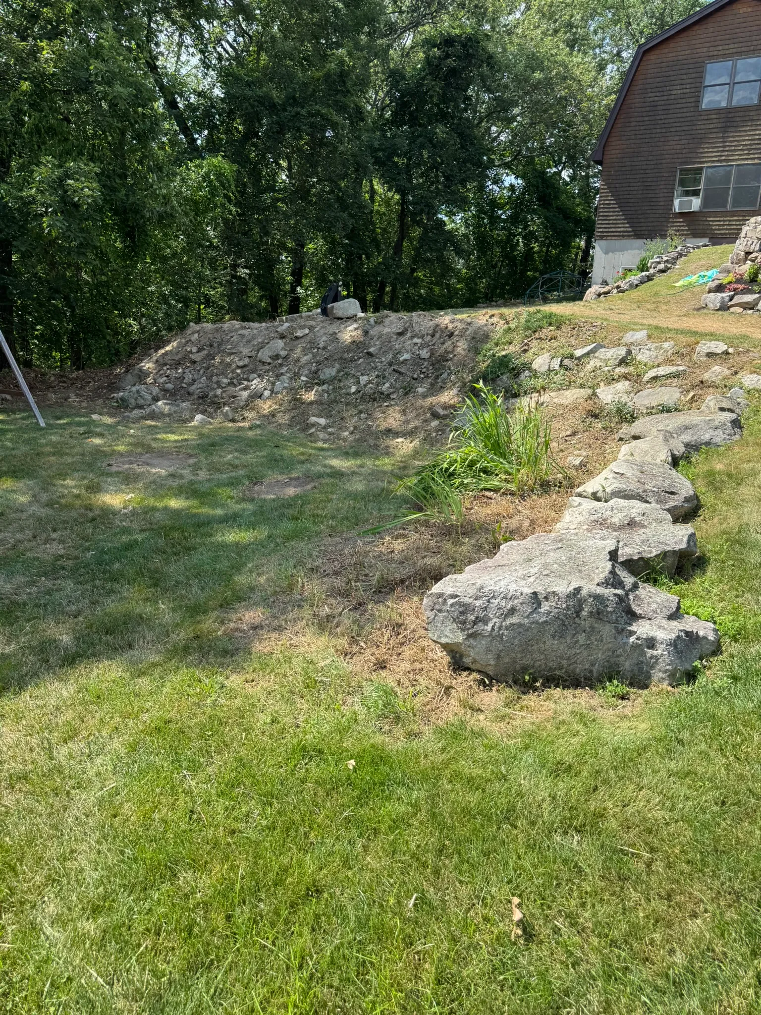 A natural stone retaining wall and plantings built on an established Concord, MA property