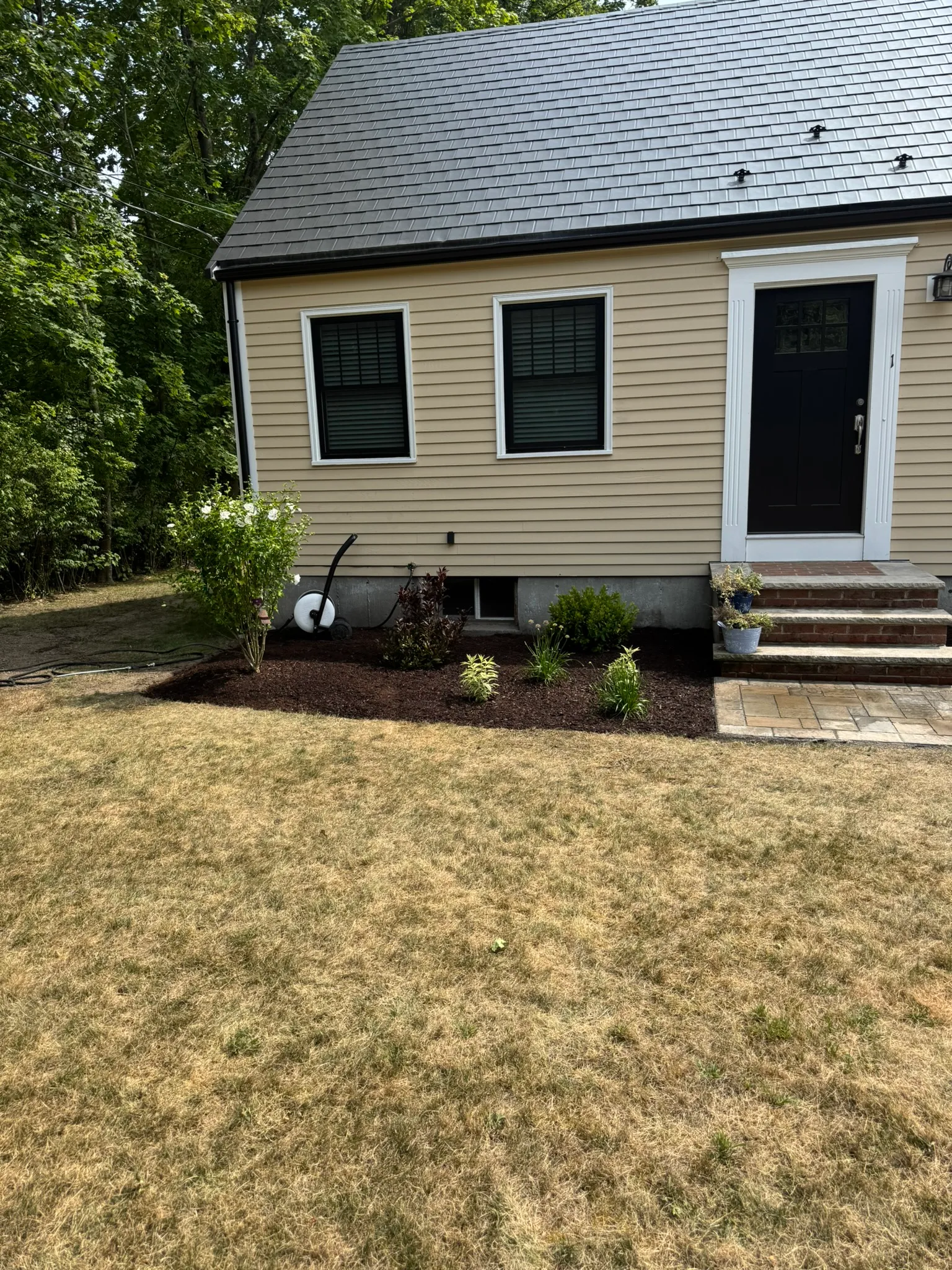 A finished front yard with fresh mulch beds and new plantings along the foundation